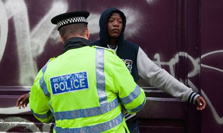 A young black man is searched by a Metropolitan police officer in London
